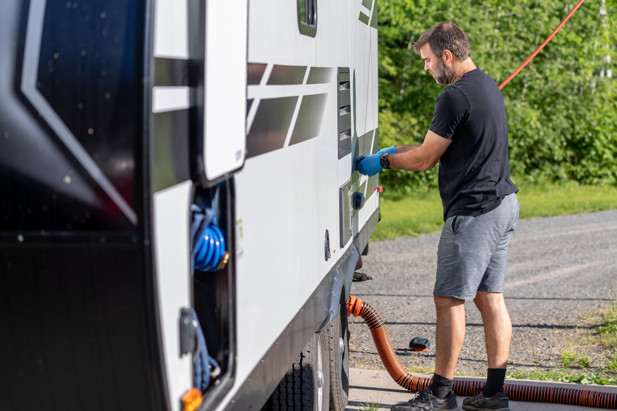 Man Emptying RV Sewer at Dump Station After Camping