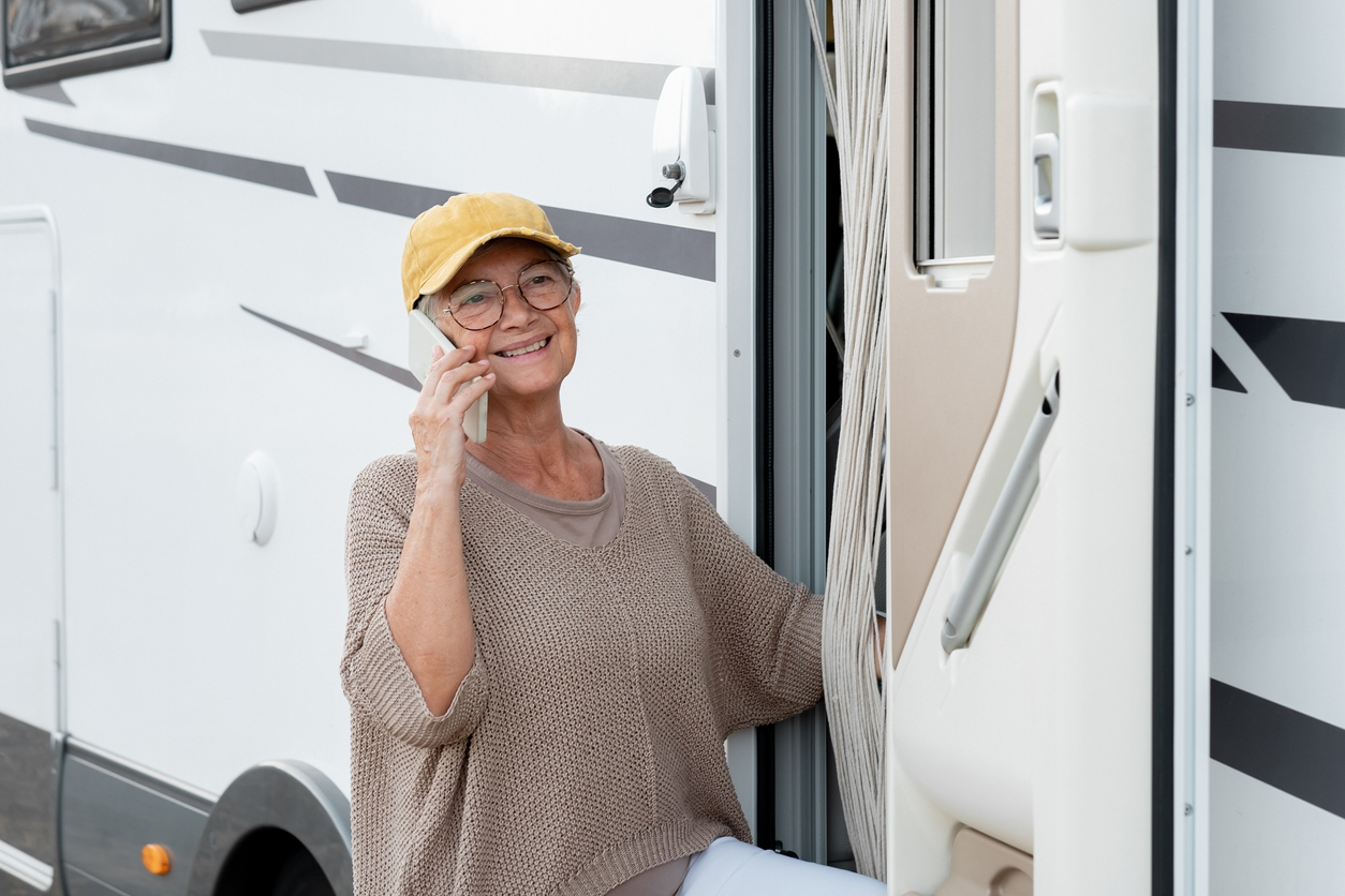 Senior woman standout outside her RV on her cell phone