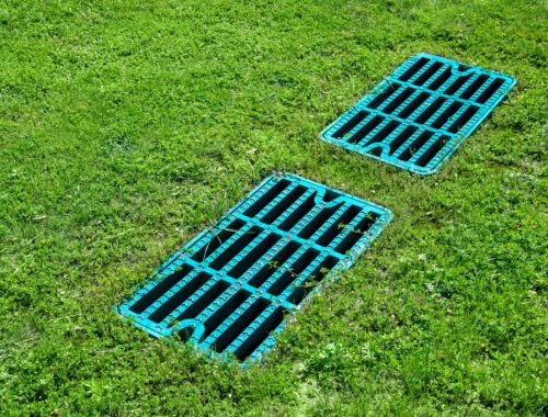 manhole drainage grates on the lawn with green grass septic tank cover, sump cesspool drainage system environment design side view with copy space, nobody.